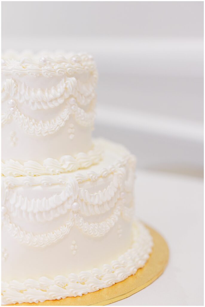 Close-up of a two-tier white wedding cake with piped details, shown at Pembroke Pines Country Club in Pembroke, NH.