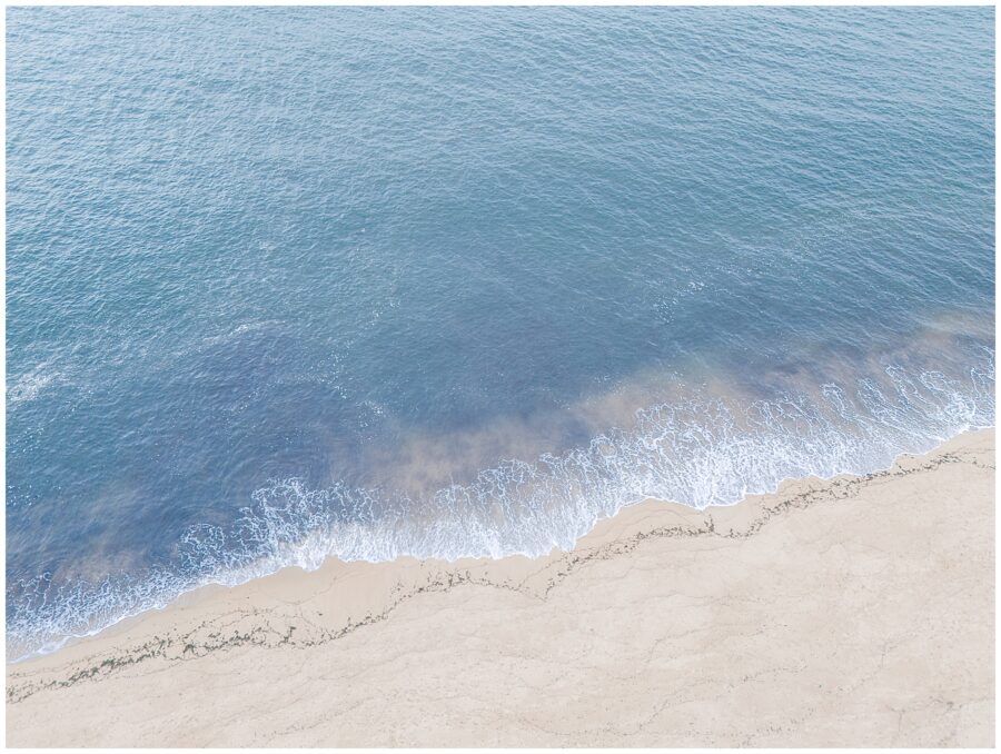 A high-angle view of the calm ocean waters meeting the sandy shore at a private beach in Newburyport, MA, during a senior photo session.