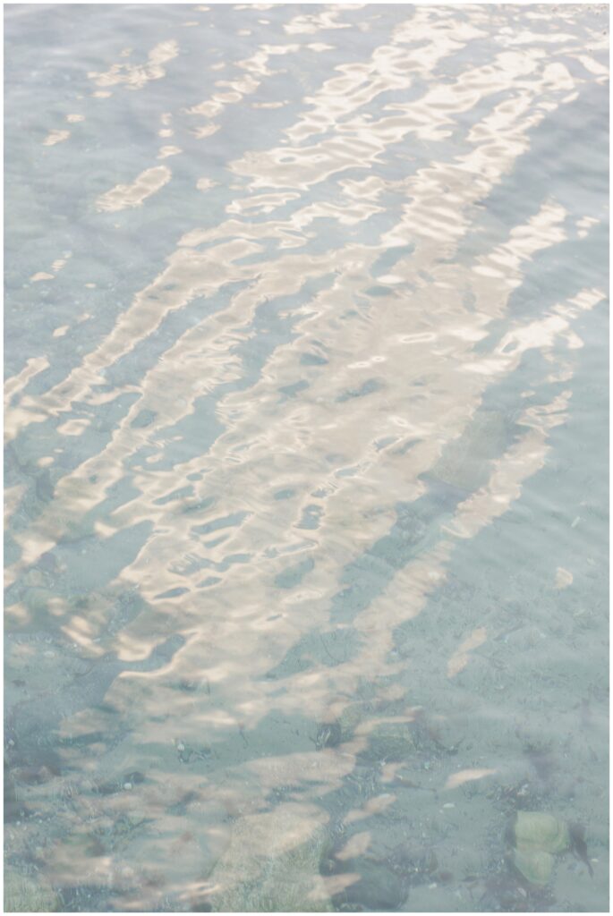  Close-up of gentle ocean water with soft ripples reflecting the light, creating a serene effect. Taken at a Cohasset Beach, the image captures the peaceful, clear coastal water.