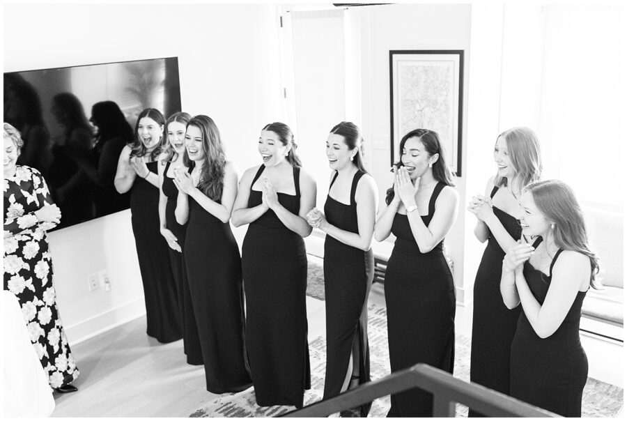 The bridesmaids burst into expressions of surprise and excitement upon seeing the bride, in a candid black-and-white photo by a Washington D.C. wedding photographer.
