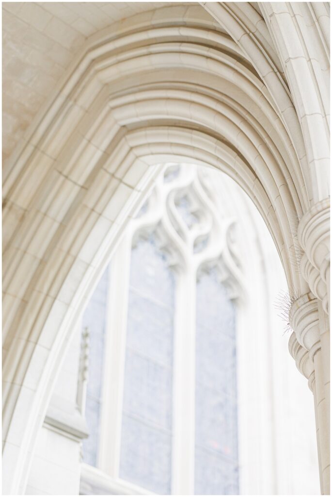 A close-up of the ornate Gothic arch with a stained glass window in soft focus behind, showcasing the architectural beauty of the Washington National Cathedral.