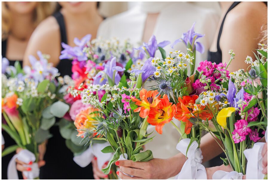 A close-up view of several bridesmaids’ bouquets featuring orange, purple, yellow, and white flowers at a Washington National Cathedral wedding.