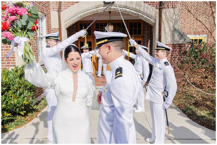 The bride and groom laugh while walking beneath a military sword arch outside the National Cathedral School following their wedding ceremony.