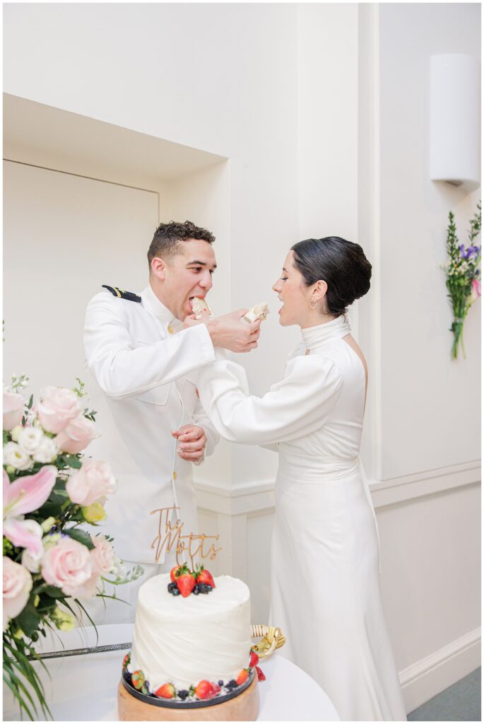 Bride and groom feed each other pieces of wedding cake during their National Cathedral School reception.