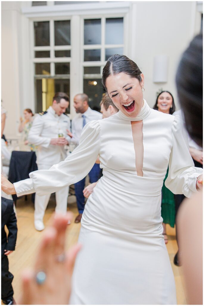 The bride dances with a joyful expression during the National Cathedral School wedding reception, surrounded by guests.