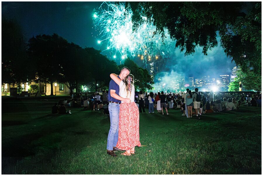 A couple embraces joyfully under fireworks in Boston after a proposal, showing one of the most memorable marriage proposal ideas Boston.