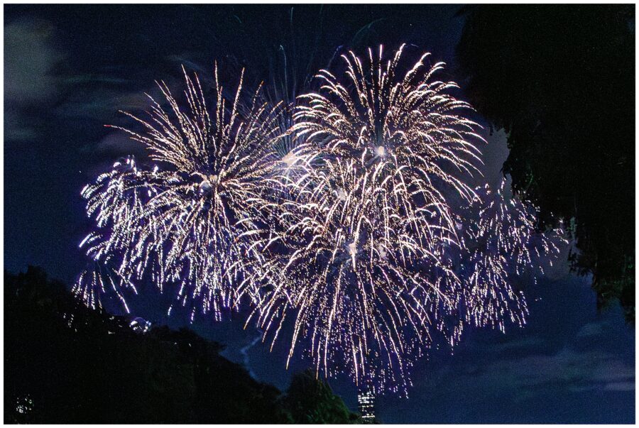 A dramatic close-up of bright white fireworks bursting over Boston, capturing the energy of the 4th of July celebration.