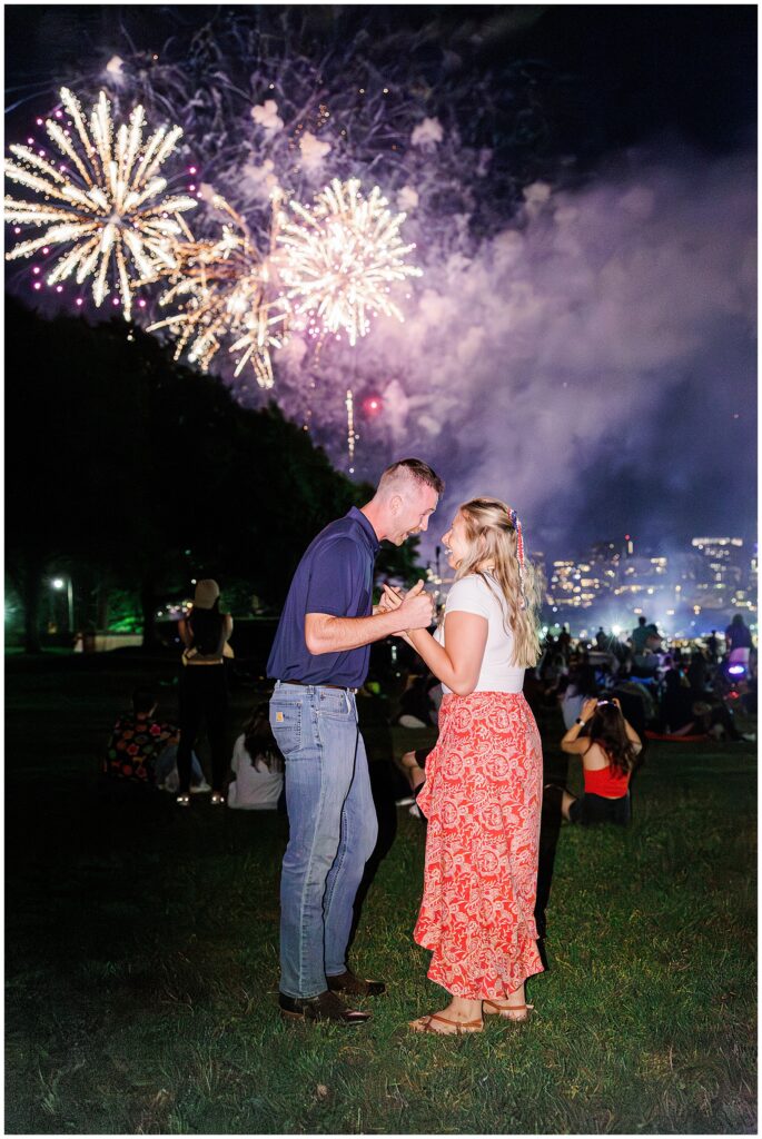 Newly engaged couple shares a joyful moment under fireworks in Boston, a scene full of romantic energy and marriage proposal ideas Boston.
