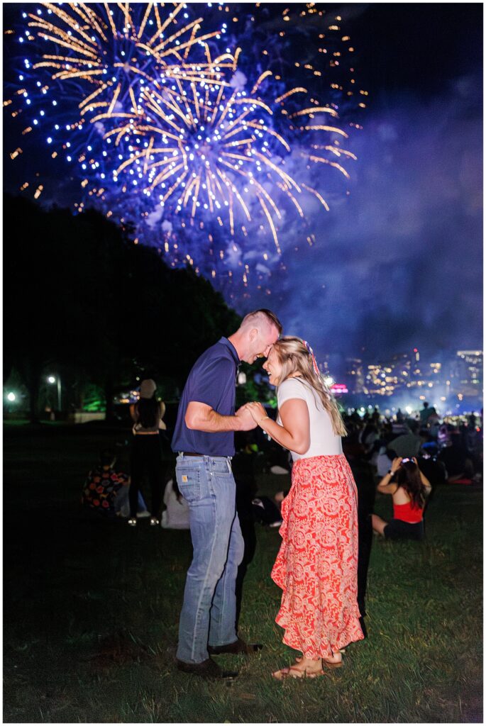 Couple laughs under vibrant blue fireworks in Boston, celebrating their engagement—one of the most magical marriage proposal ideas Boston.