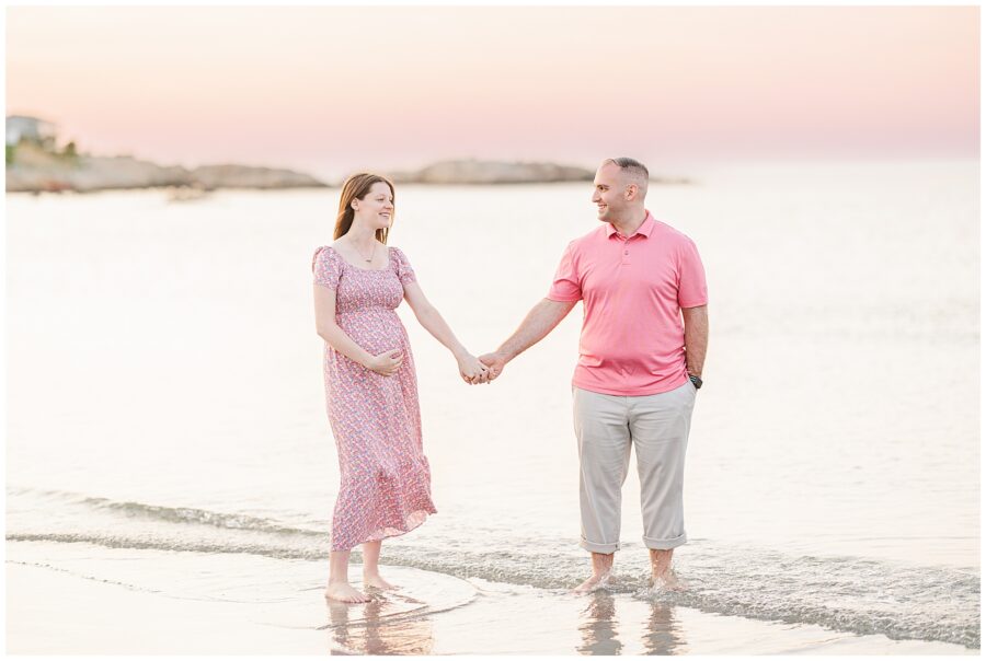 Couple holding hands while standing barefoot in the surf at Wingaersheek Beach during sunset.