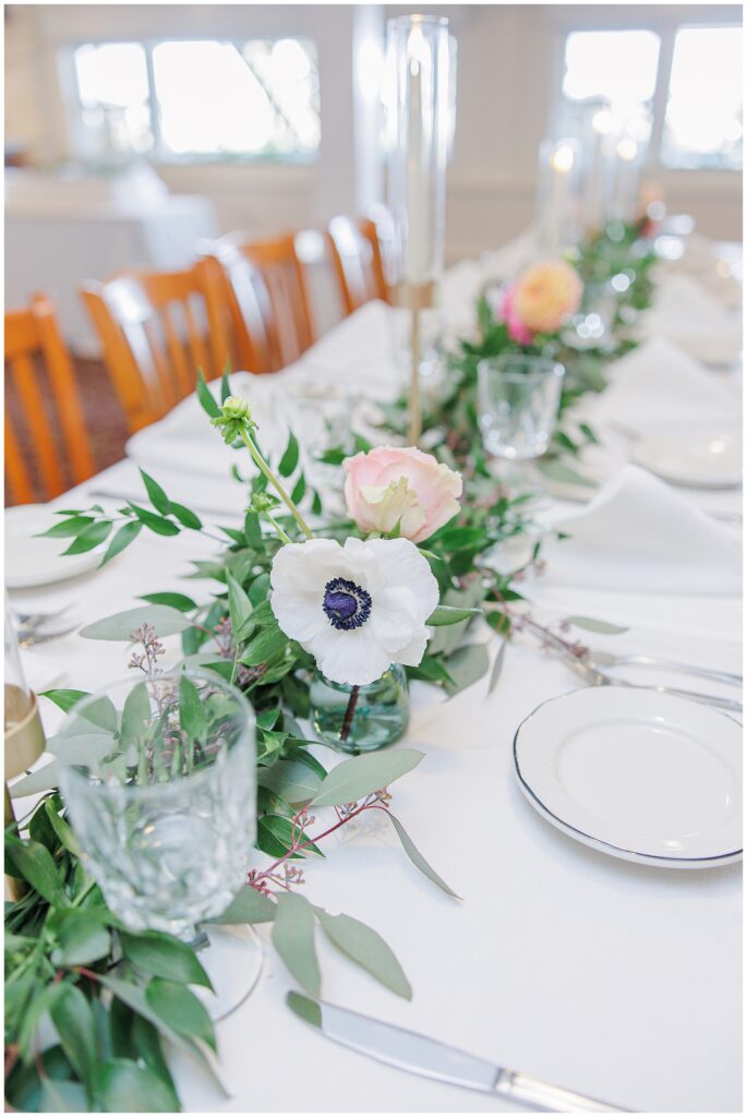 Wedding reception table decorated with lush greenery, taper candles, and pastel floral centerpieces. A refined Cape Cod wedding reception detail photographed by a Cape Cod wedding photographer.