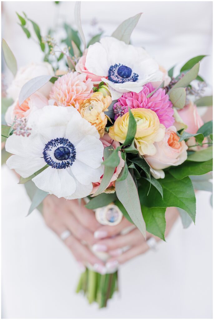 Close-up of vibrant bridal bouquet with white anemones, peach roses, ranunculus, and dahlias. A romantic wedding floral detail photographed on Cape Cod.