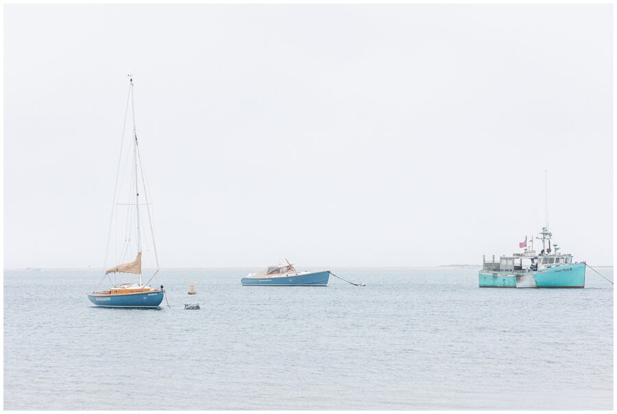 Blue and teal fishing boats anchored in calm Cape Cod waters off Chatham Bars Inn’s private beach