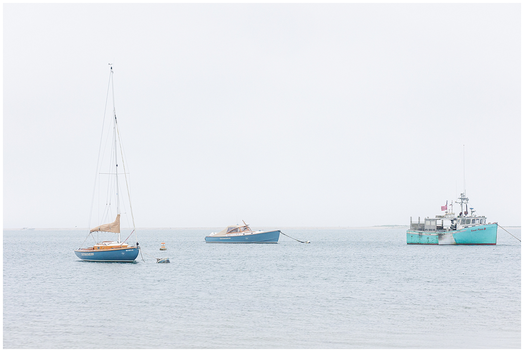 Blue and teal fishing boats anchored in calm Cape Cod waters off Chatham Bars Inn’s private beach