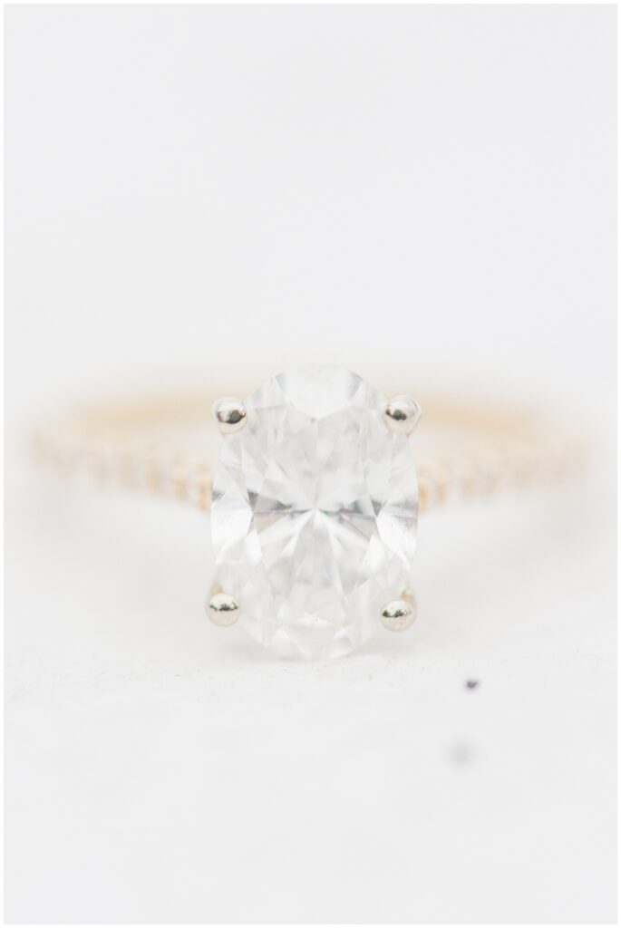 Close-up of oval diamond engagement ring on a gold band against a clean white background