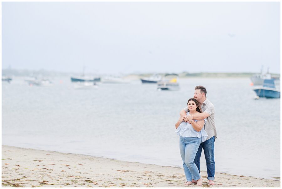 Couple smiling at each other on the shoreline of Chatham Bars Inn during engagement session