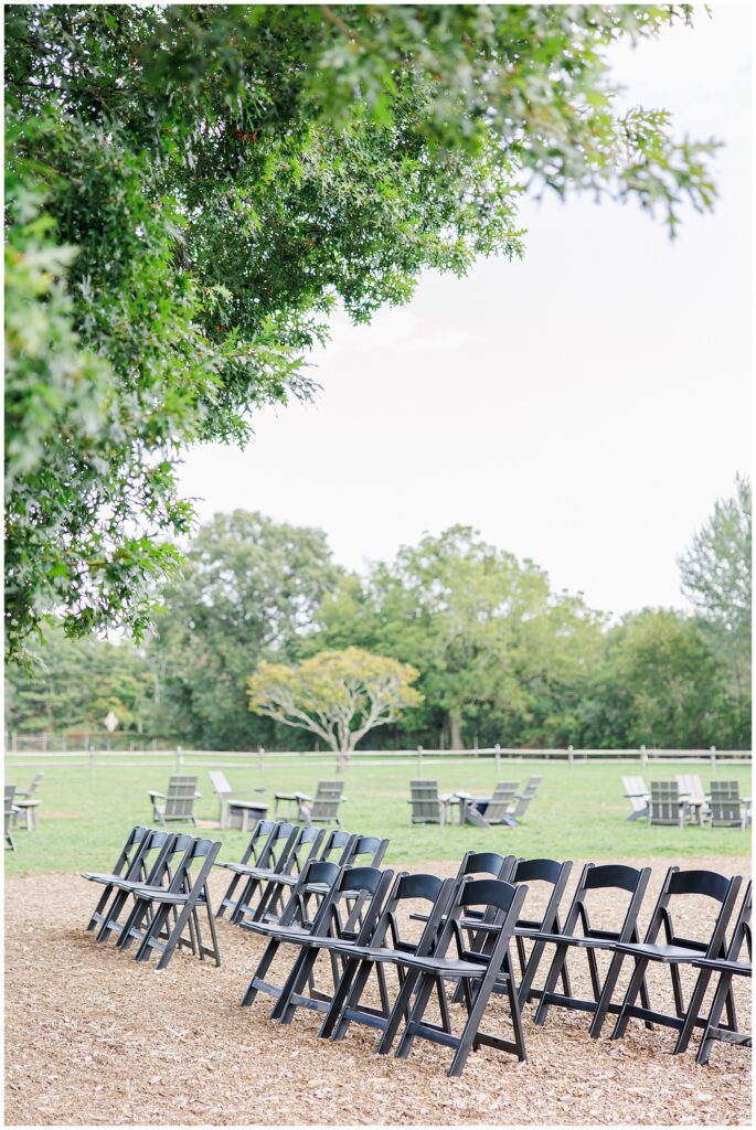 Rows of black folding chairs set up outdoors for a wedding ceremony.
