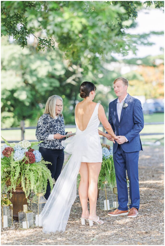 Couple holding hands during their outdoor ceremony with the officiant, captured by a Boston Elopement Photographer.
