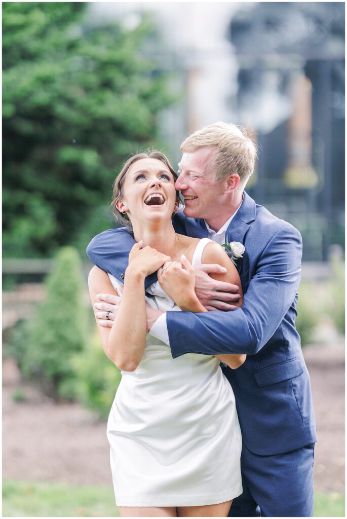 Groom hugging the bride from behind as she laughs, captured by a Boston Elopement Photographer.