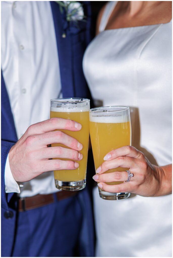 Close-up of the couple clinking glasses of beer during their Boston elopement celebration.