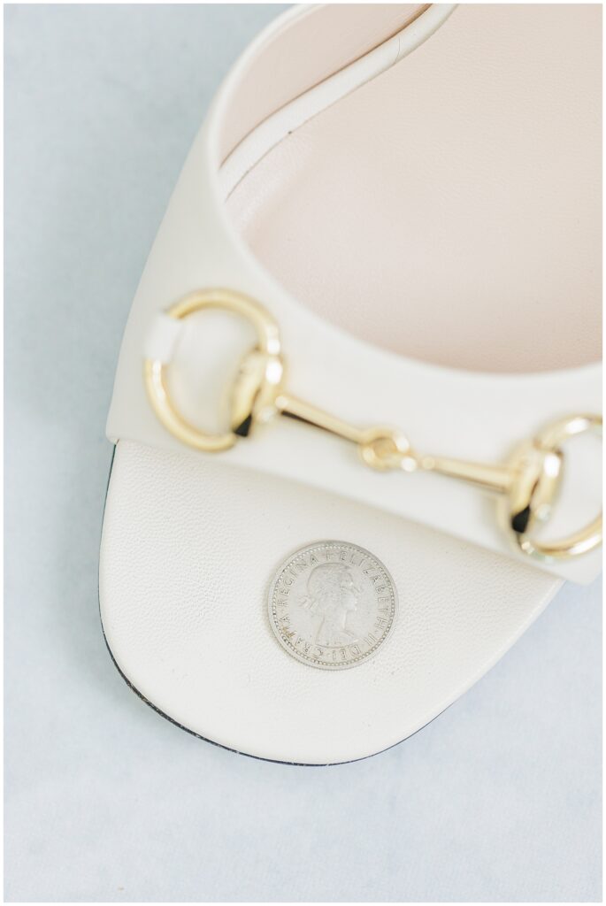 White Gucci sandal with a gold horsebit detail and a silver coin placed on the insole, part of wedding detail photography at Nauset Beach Inn.