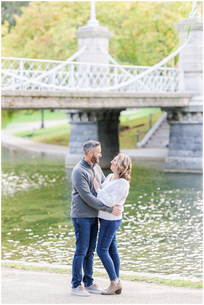 The couple shares a joyful moment by the pond, holding each other in front of the iconic white bridge.