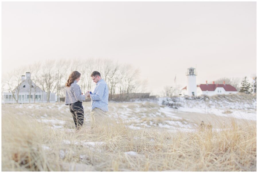 Newly engaged couple admiring the ring after their Chatham Lighthouse Beach proposal at Chatham Lighthouse Beach in Chatham, MA Cape Cod.