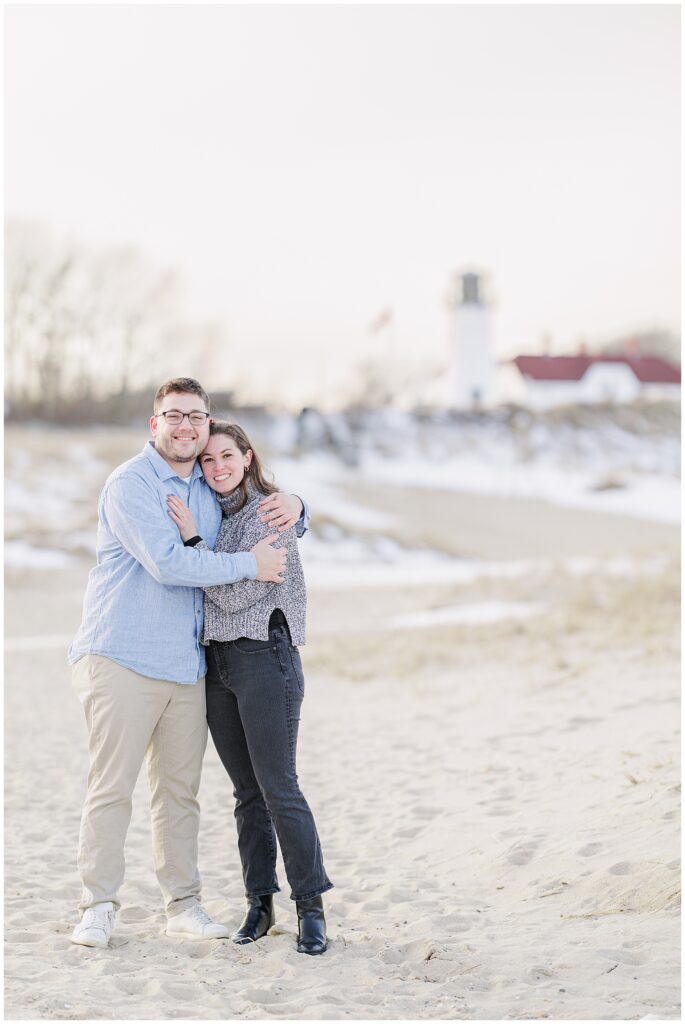 Portrait of newly engaged couple smiling at camera after their Chatham Lighthouse Beach proposal at Chatham Lighthouse Beach in Chatham, MA Cape Cod, photographed by a Cape Cod engagement photographer.