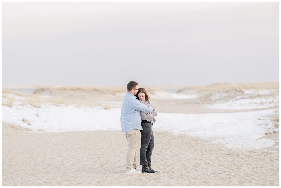 Romantic embrace in the dunes following a Chatham Lighthouse Beach proposal at Chatham Lighthouse Beach in Chatham, MA Cape Cod, captured by a Cape Cod proposal photographer.