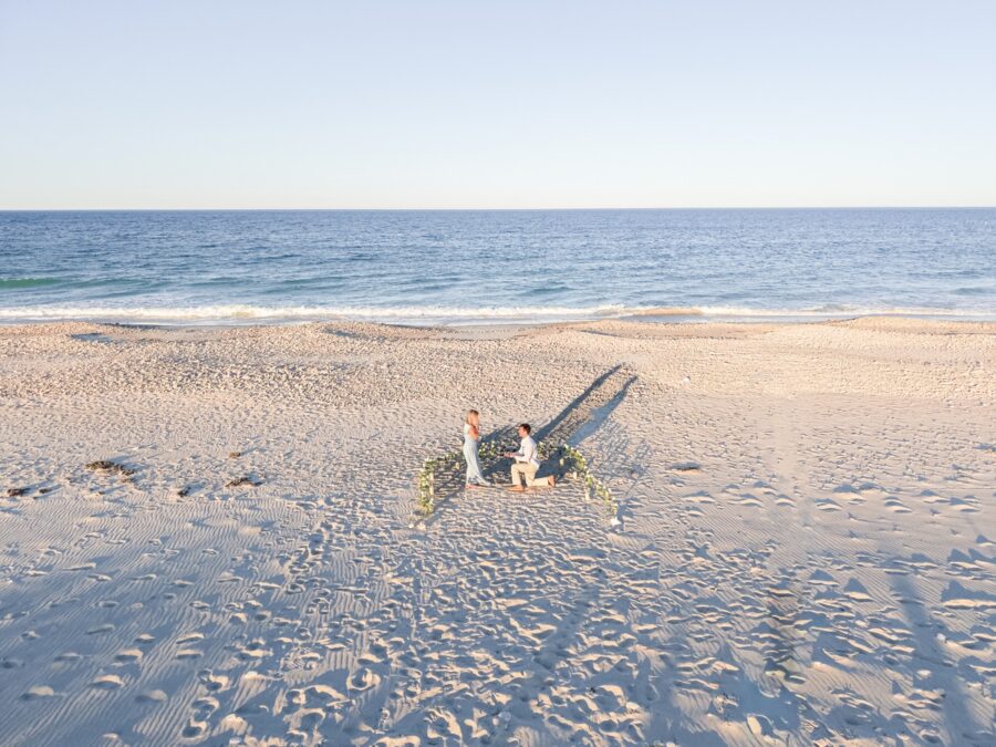 Aerial view of a Duxbury Beach proposal with a horseshoe of white roses by the ocean