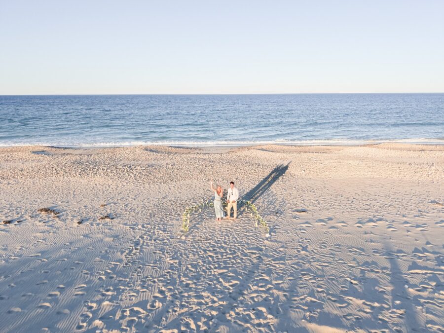Joyful just engaged couple lifting each other up on Duxbury Beach after proposal