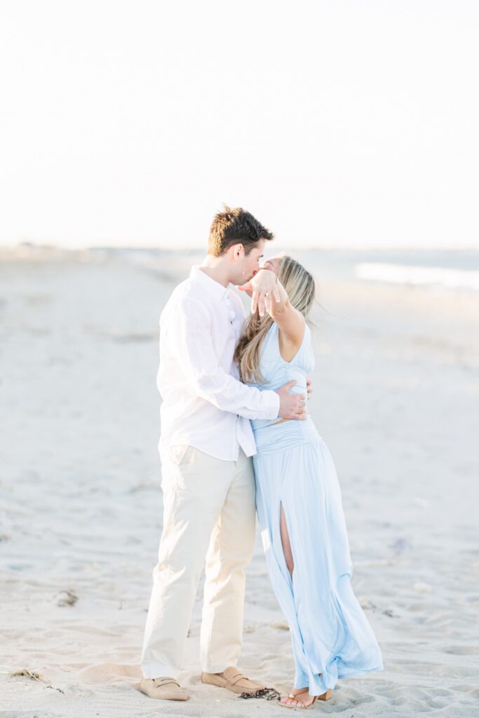Just engaged couple embracing on Duxbury Beach with soft sunset light after proposal