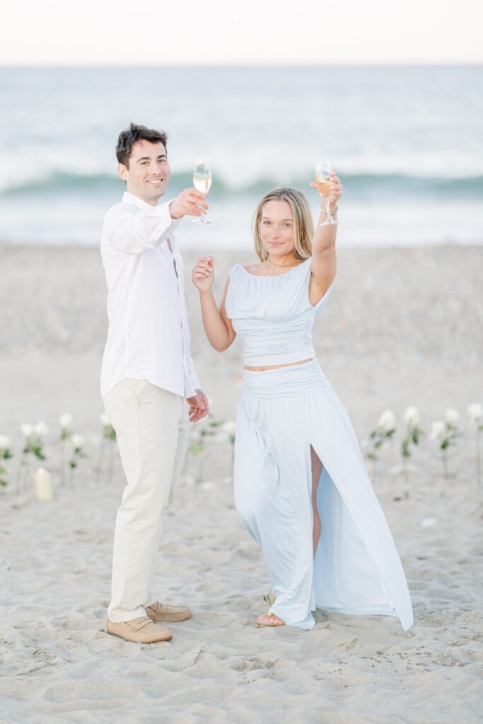 Couple toasting with champagne on Duxbury Beach after their proposal