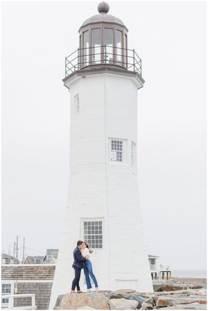 Wide portrait of couple kissing after Scituate Lighthouse proposal with lighthouse in background
