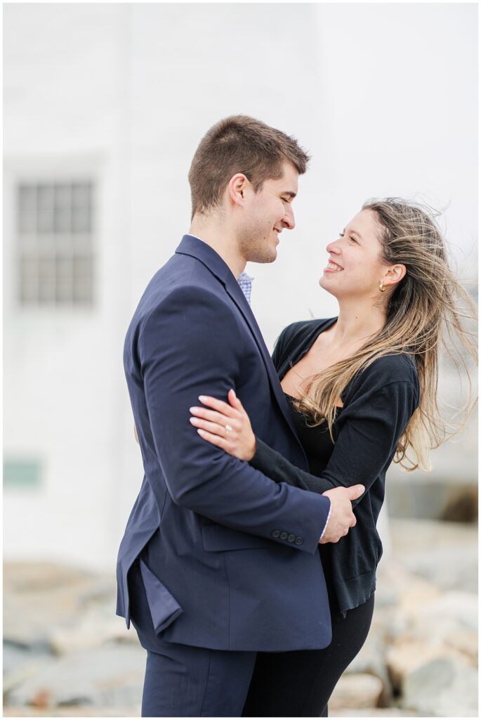 Romantic portrait of couple embracing after Scituate Lighthouse proposal with soft coastal backdrop
