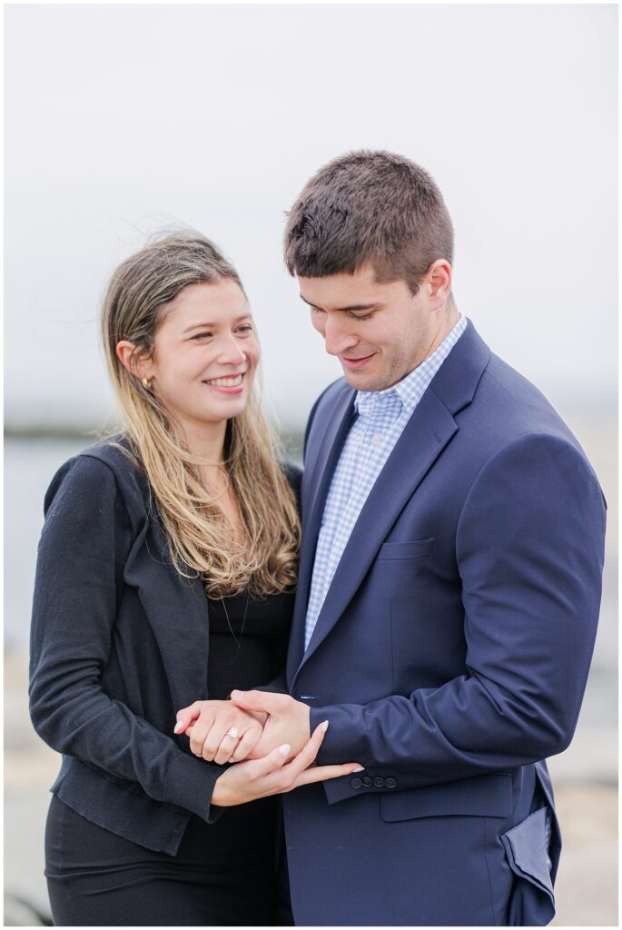 Couple smiling and admiring engagement ring after Scituate Lighthouse proposal in Scituate Massachusetts