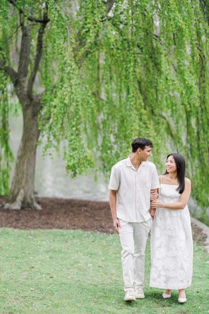     Couple walking together beneath willow trees in the Boston Public Garden during a Beacon Hill engagement session