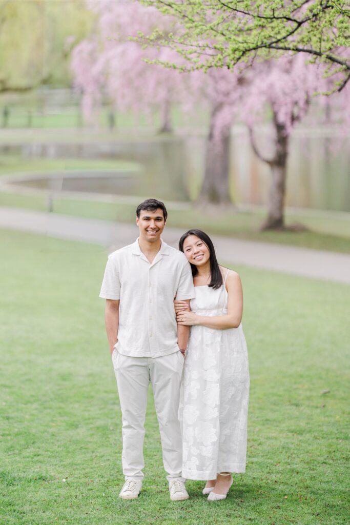     Couple posing in the Boston Public Garden with blooming cherry blossoms during Beacon Hill engagement photos