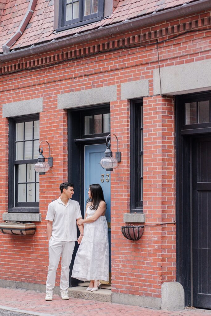     Couple standing in front of a historic Beacon Hill brownstone during romantic engagement photos in Boston
