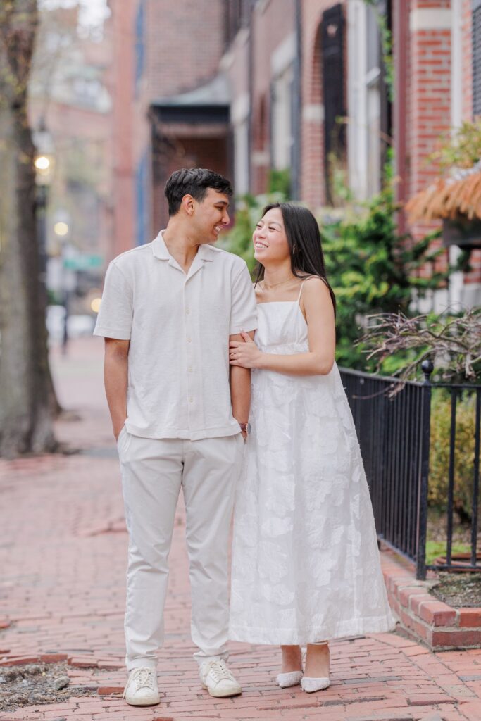     Couple walking together along a charming Beacon Hill street during elegant Boston engagement photos