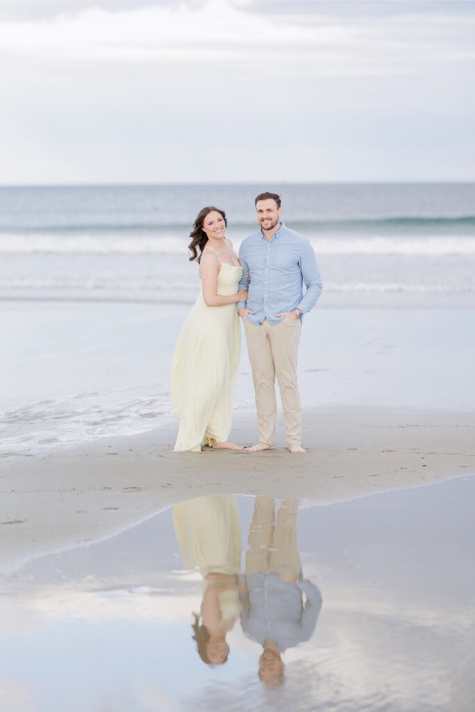     Joyful New Hampshire engagement photos with a couple standing together barefoot along the shoreline in Seabrook, New Hampshire.