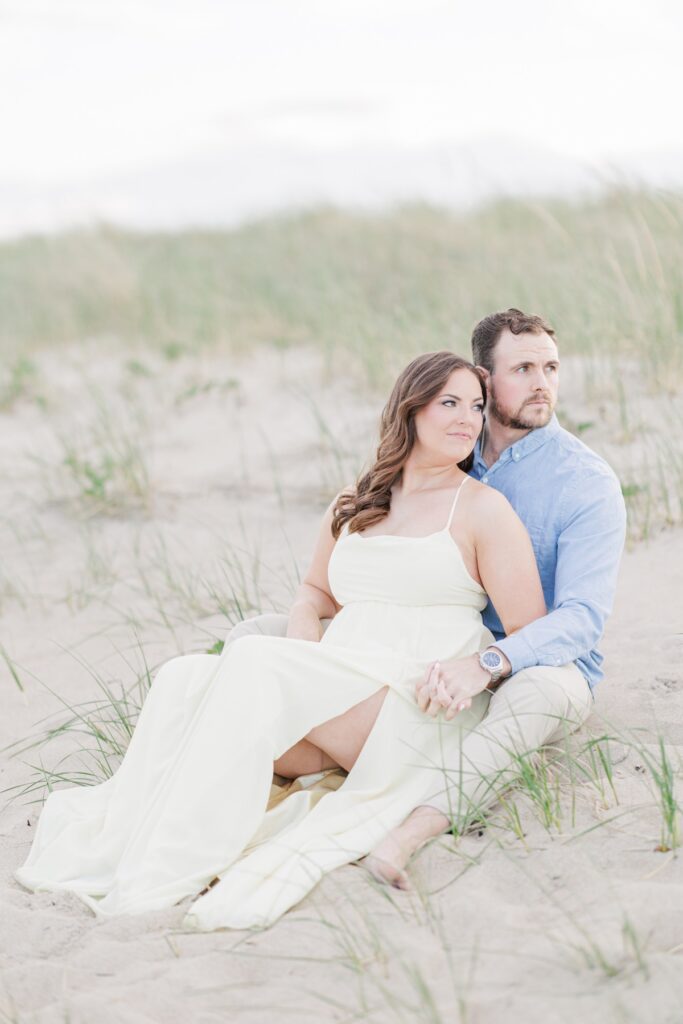     Elegant New Hampshire engagement photos of a couple sitting together in the dunes at Seabrook Beach.