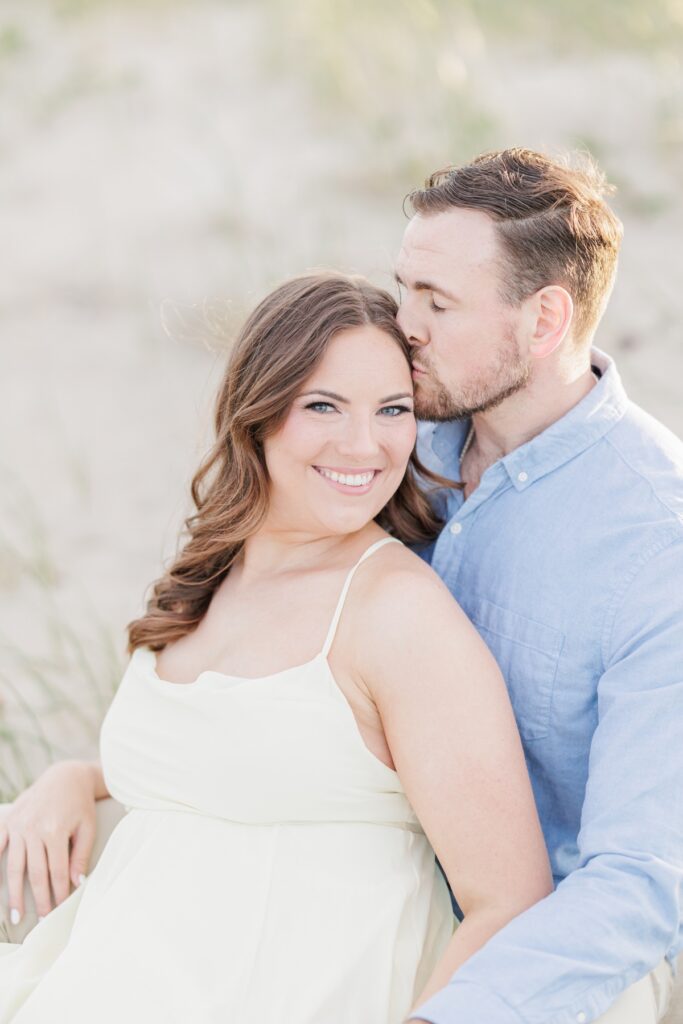     Romantic Seabrook Beach engagement photo of a groom kissing his fiancée on the forehead in the dunes.