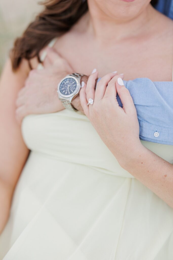     Close-up detail of an oval diamond engagement ring and intertwined hands during New Hampshire engagement photos.