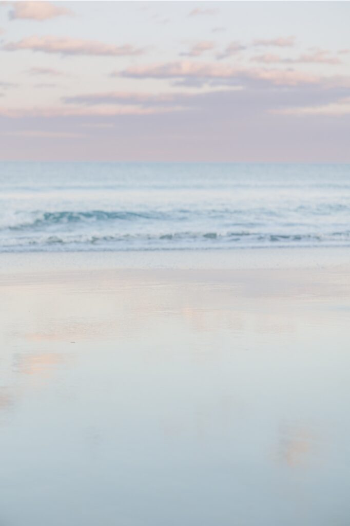 Pastel sunset over Seabrook Beach during romantic New Hampshire engagement photos along the shoreline.