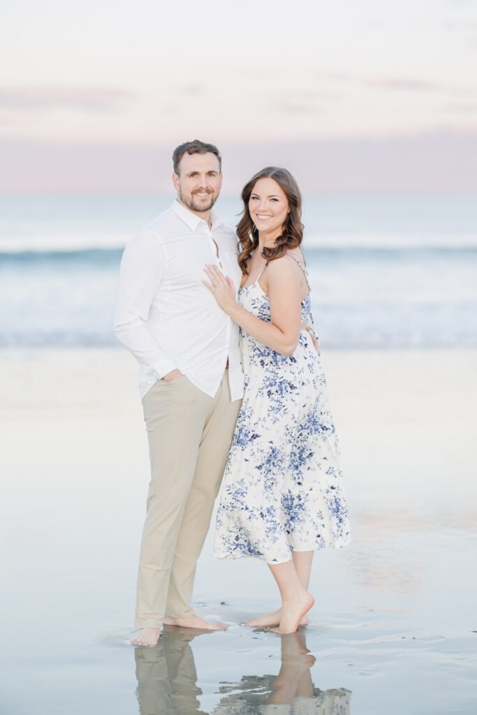    Romantic New Hampshire engagement photos of a couple standing barefoot on Seabrook Beach at sunset.