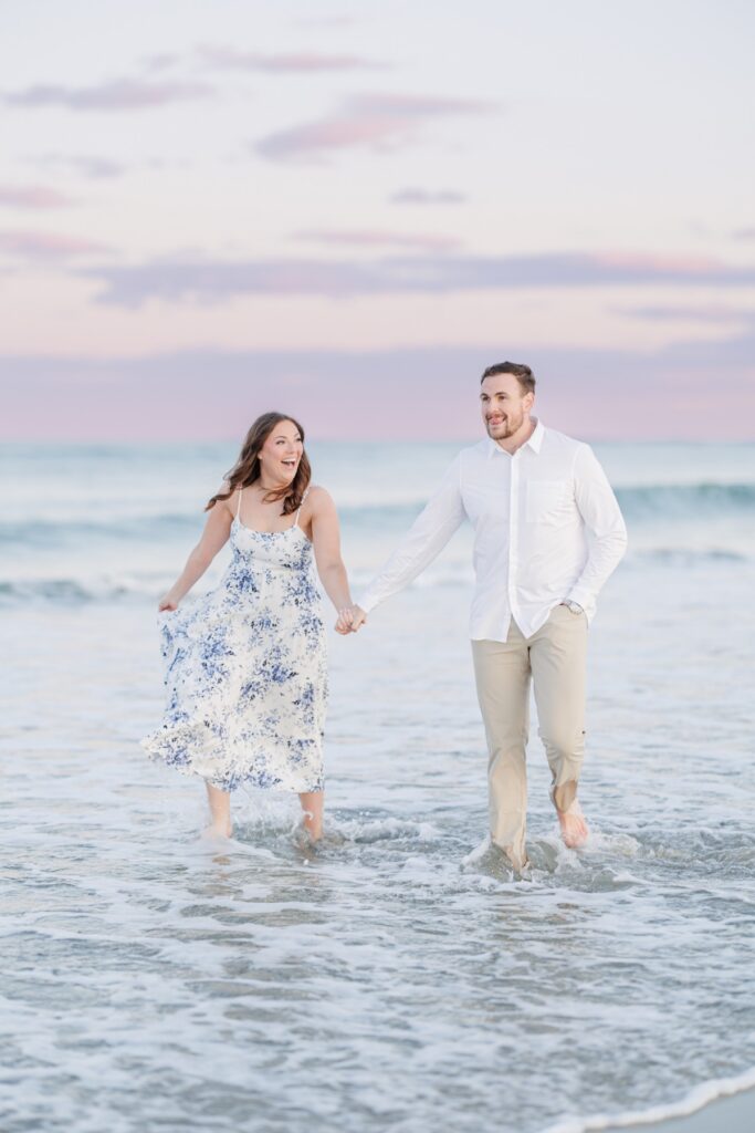     Playful Seabrook Beach engagement photos of a couple holding hands and laughing in the surf.
