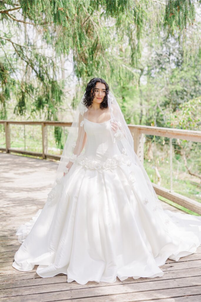 Bride wearing floral veil on a wooden bridge at Heritage Museum and Garden wedding venue