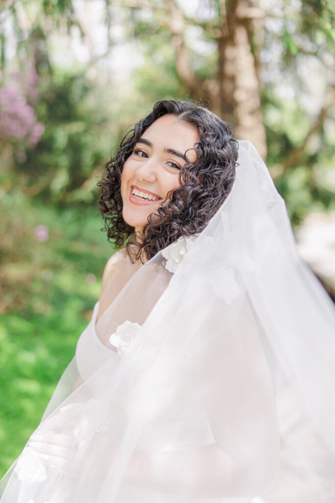 Smiling bride surrounded by greenery at Heritage Museums & Gardens in Sandwich Massachusetts