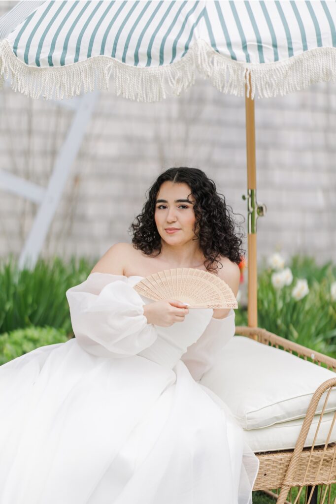 Bridal portrait beneath a striped umbrella near the windmill at Heritage Museum and Garden wedding venue